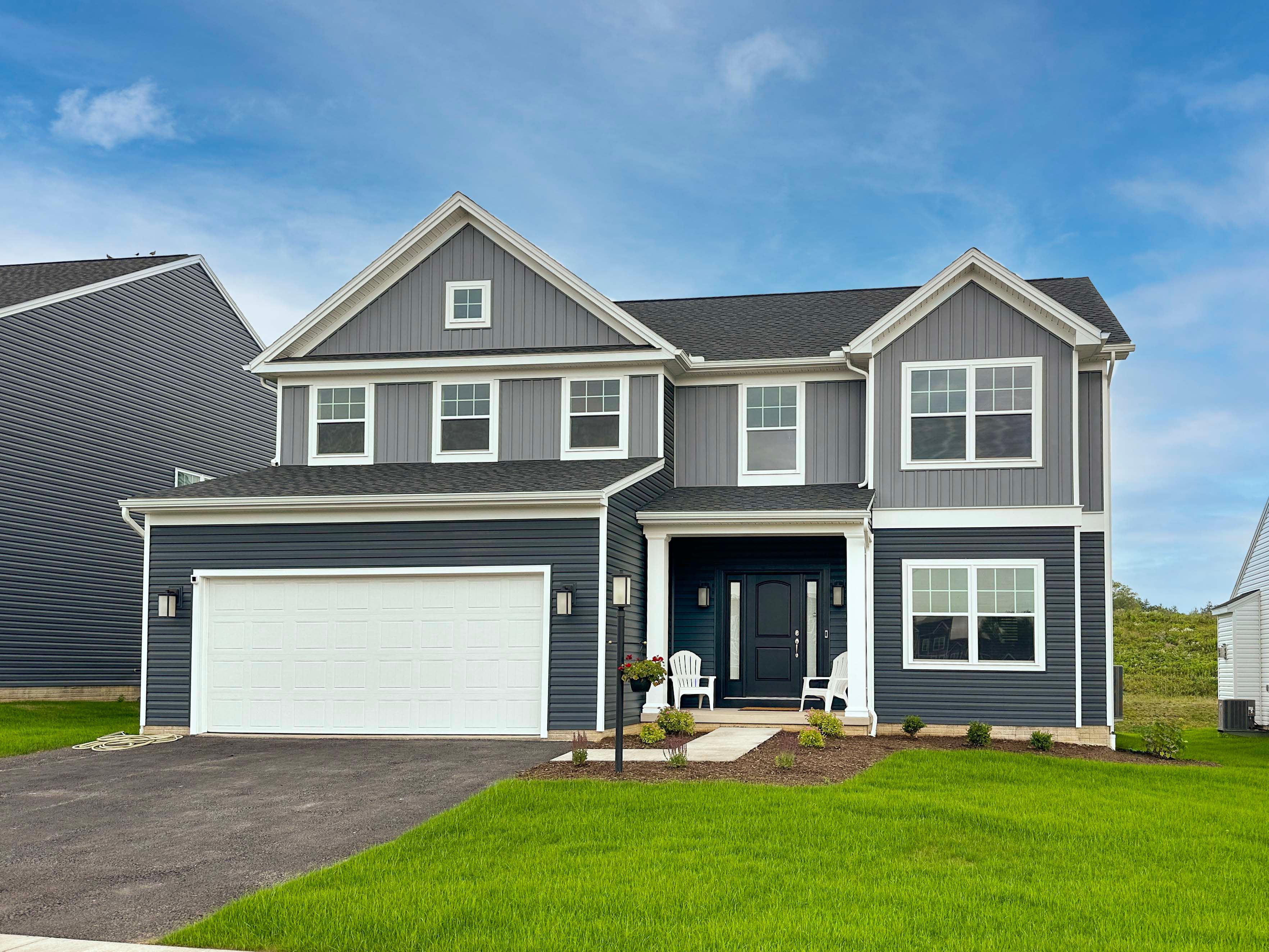 2-story home with siding front, partial covered porch and two car front entry garage.