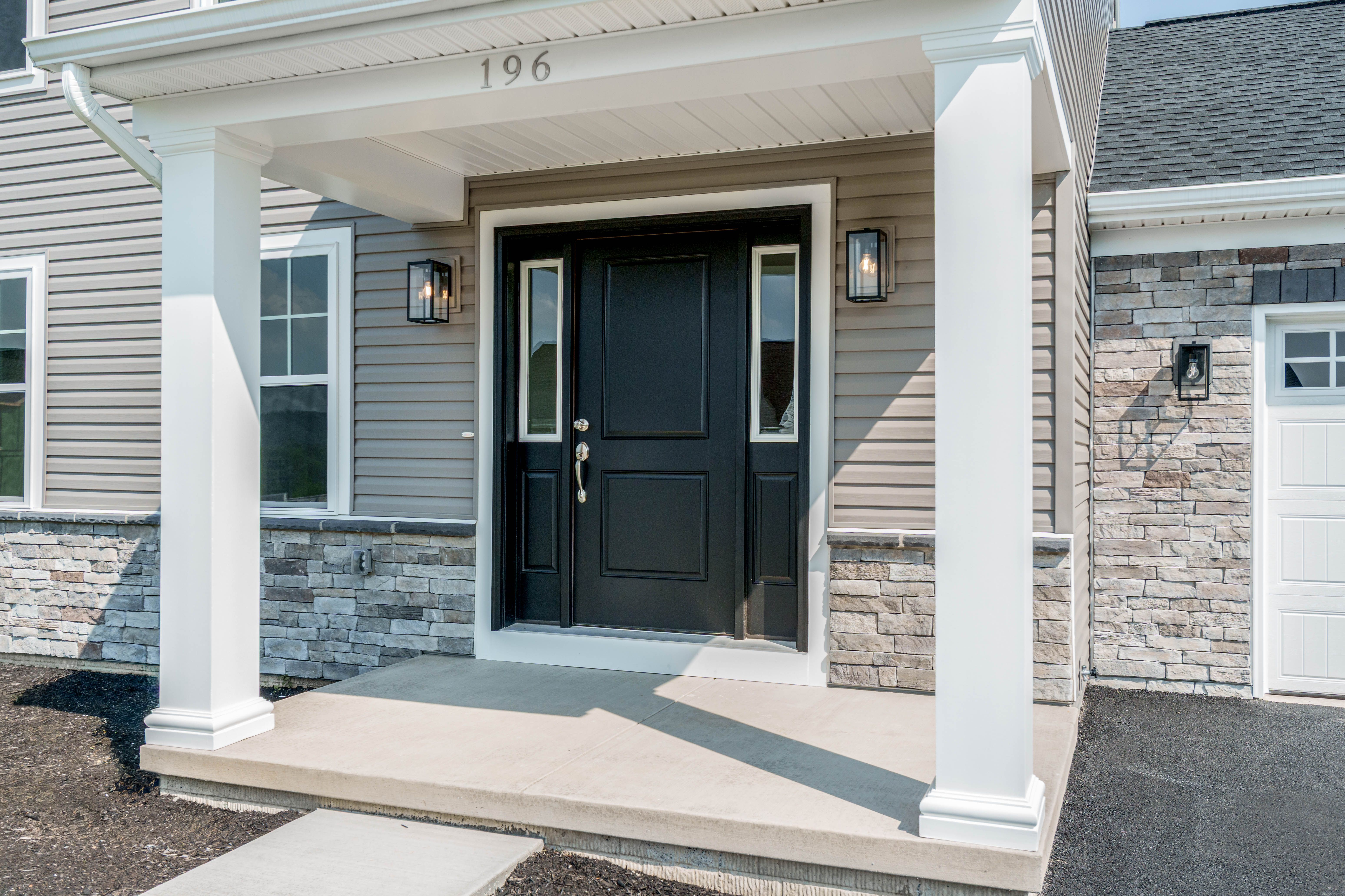 Covered front porch with white columns and a black front door featuring sidelights.
