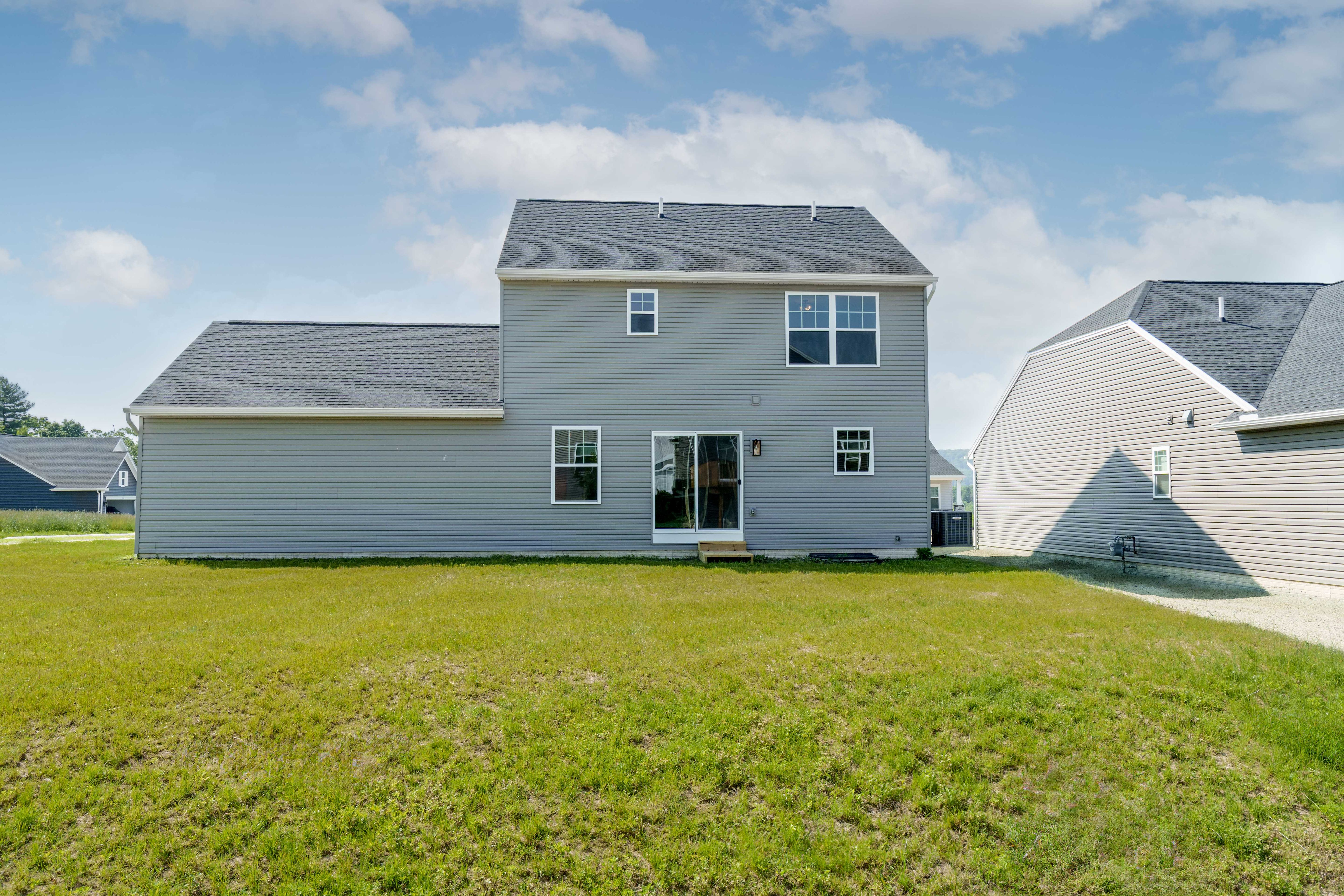 Rear exterior of the home with large backyard, sliding door, and second-story windows.