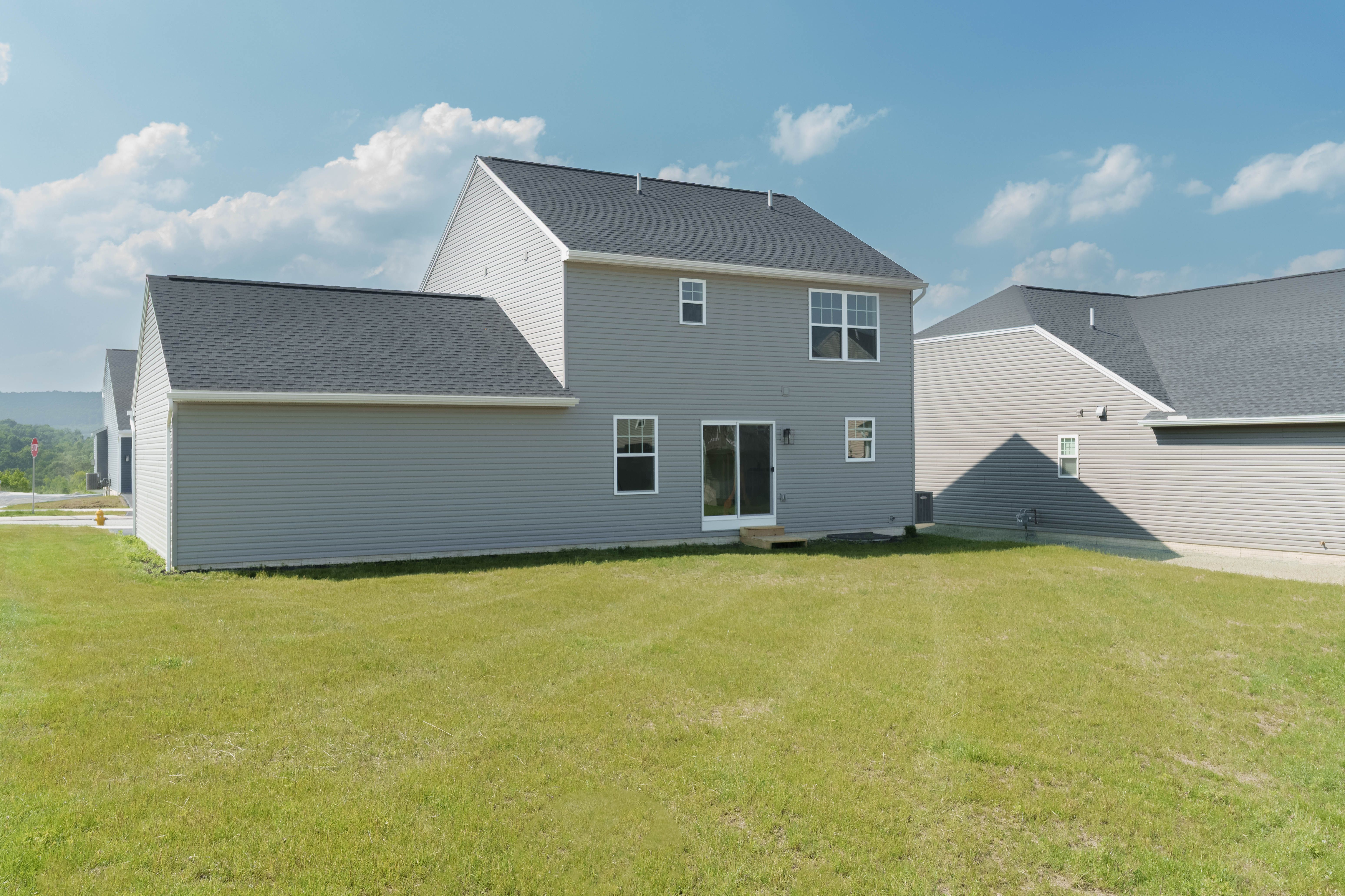 Rear exterior of the home with large backyard, sliding door, and second-story windows.