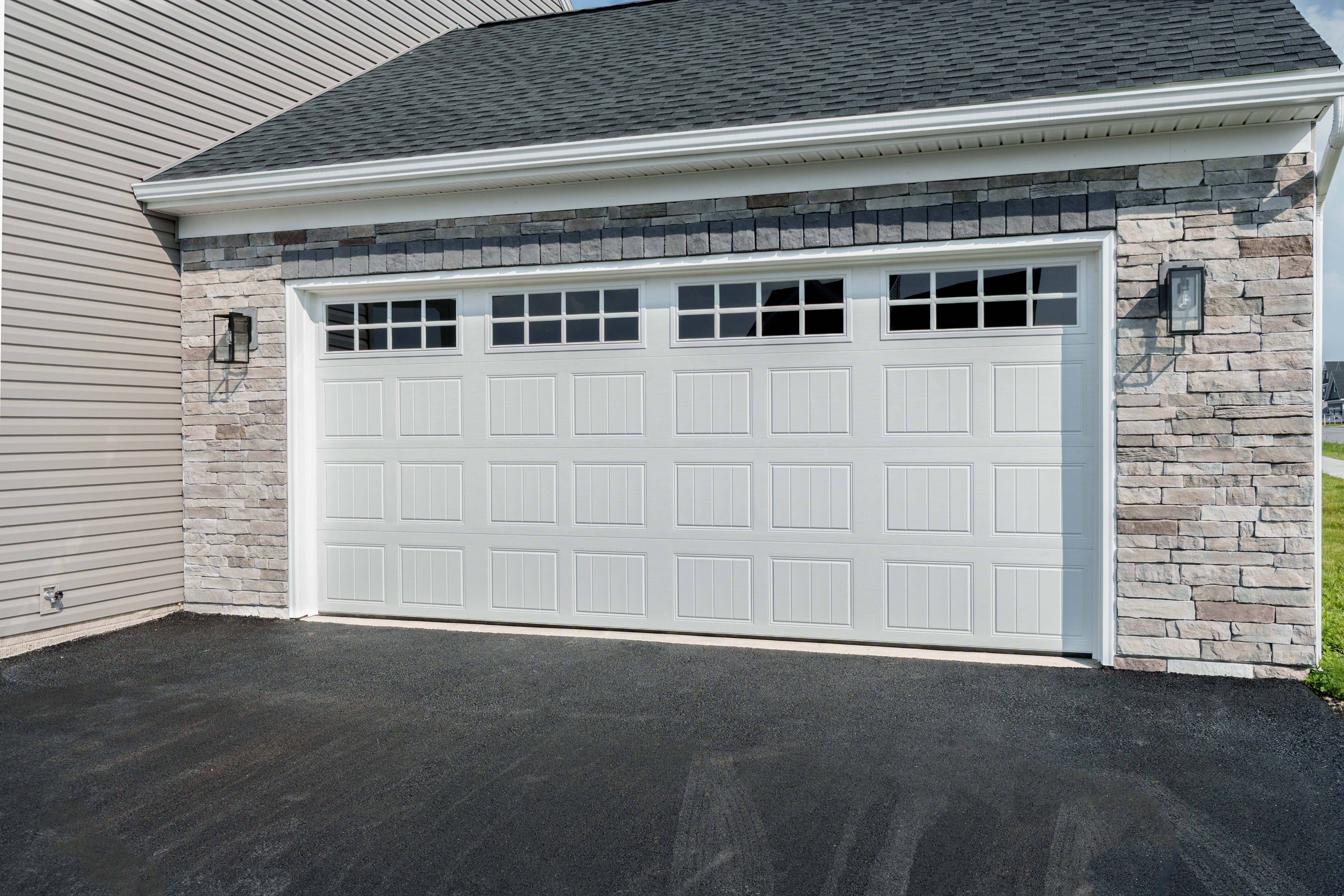 White garage door with grid windows and stone accents on the exterior of a two-car garage.