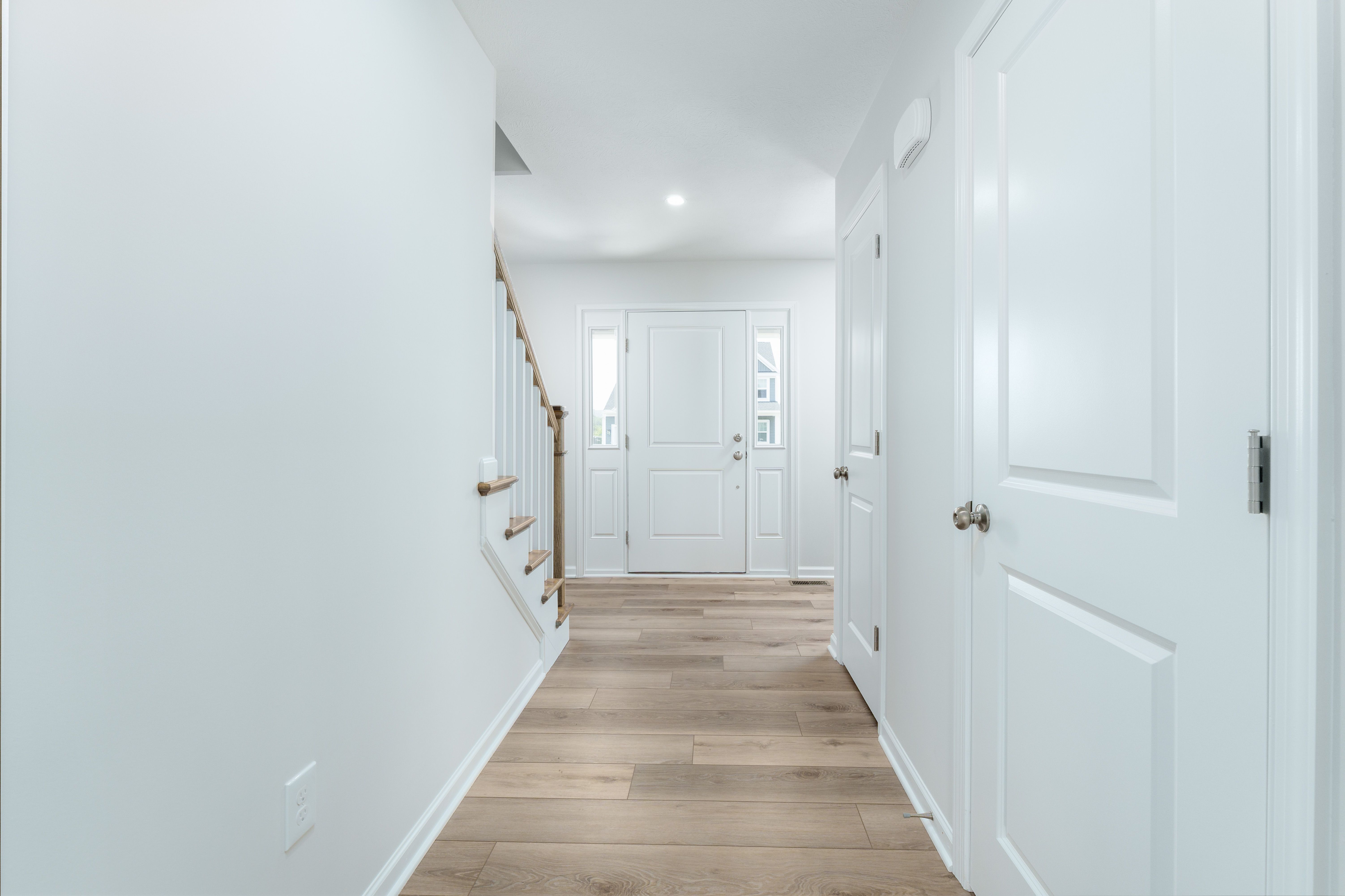 Entry hallway with luxury vinyl plank floors, front door with sidelights, and staircase on the left.