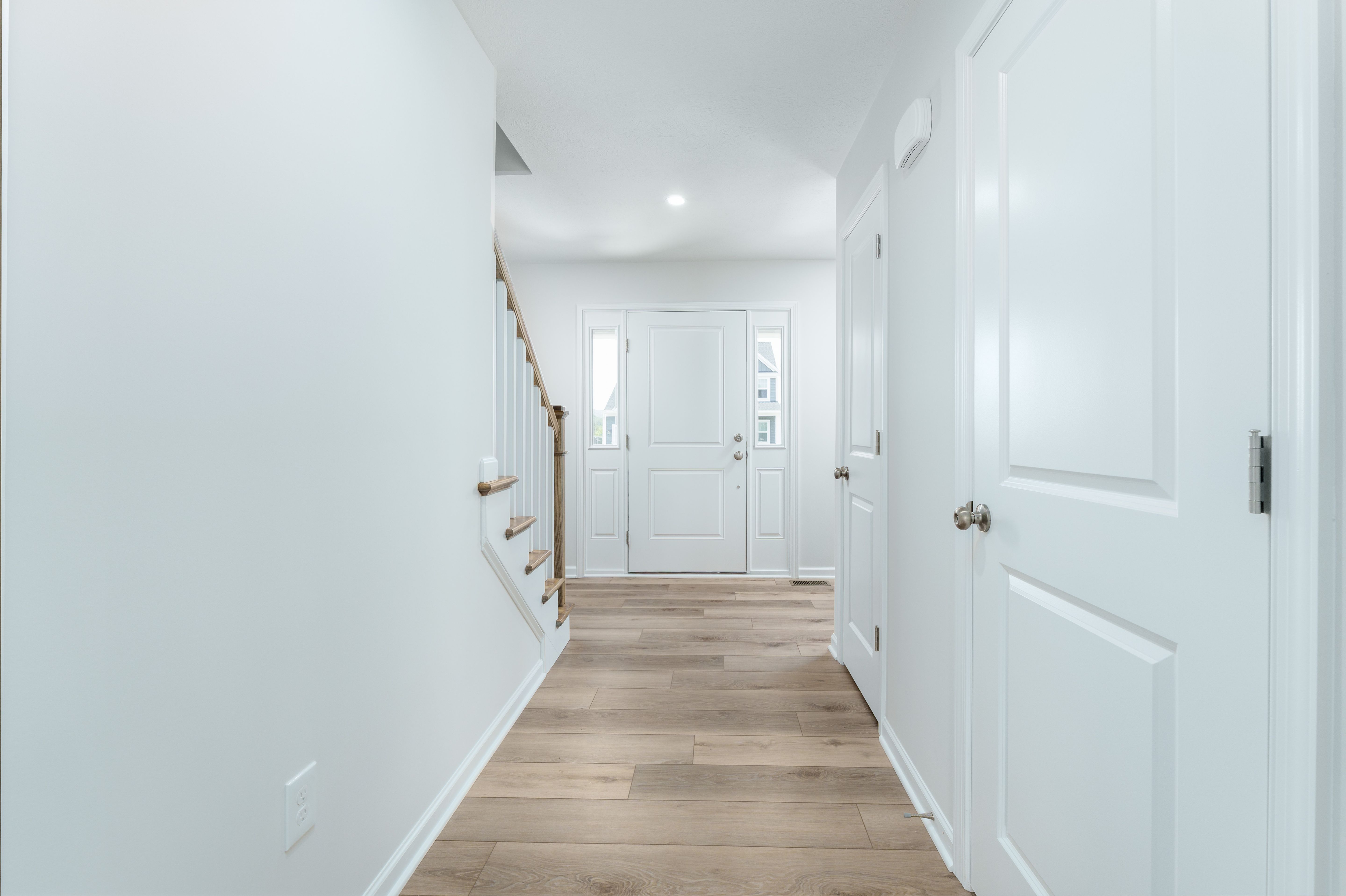 Entry hallway with luxury vinyl plank floors, front door with sidelights, and staircase on the left.