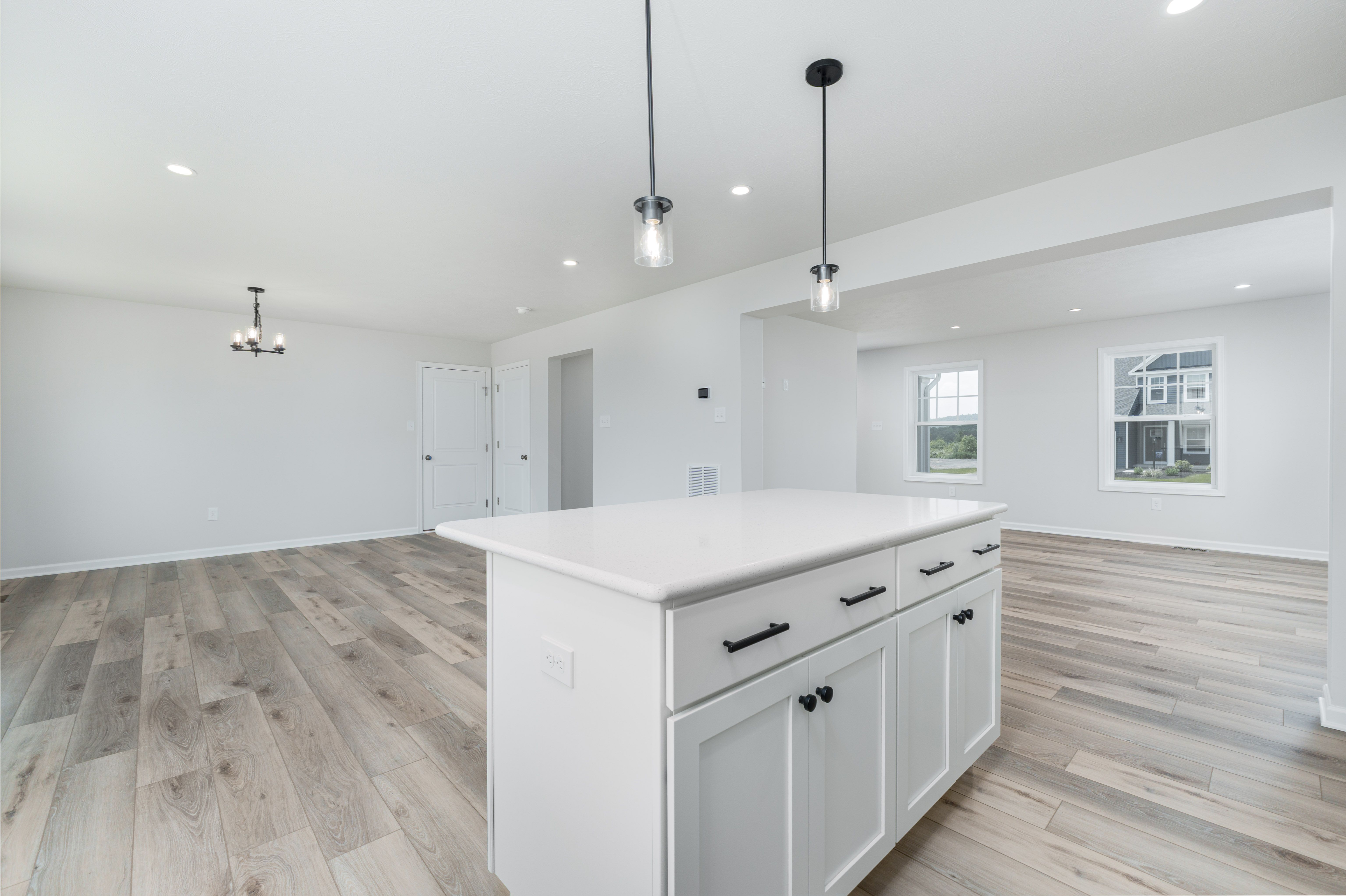 Kitchen island and breakfast area with luxury vinyl plank floors, pendant and chandelier lighting.