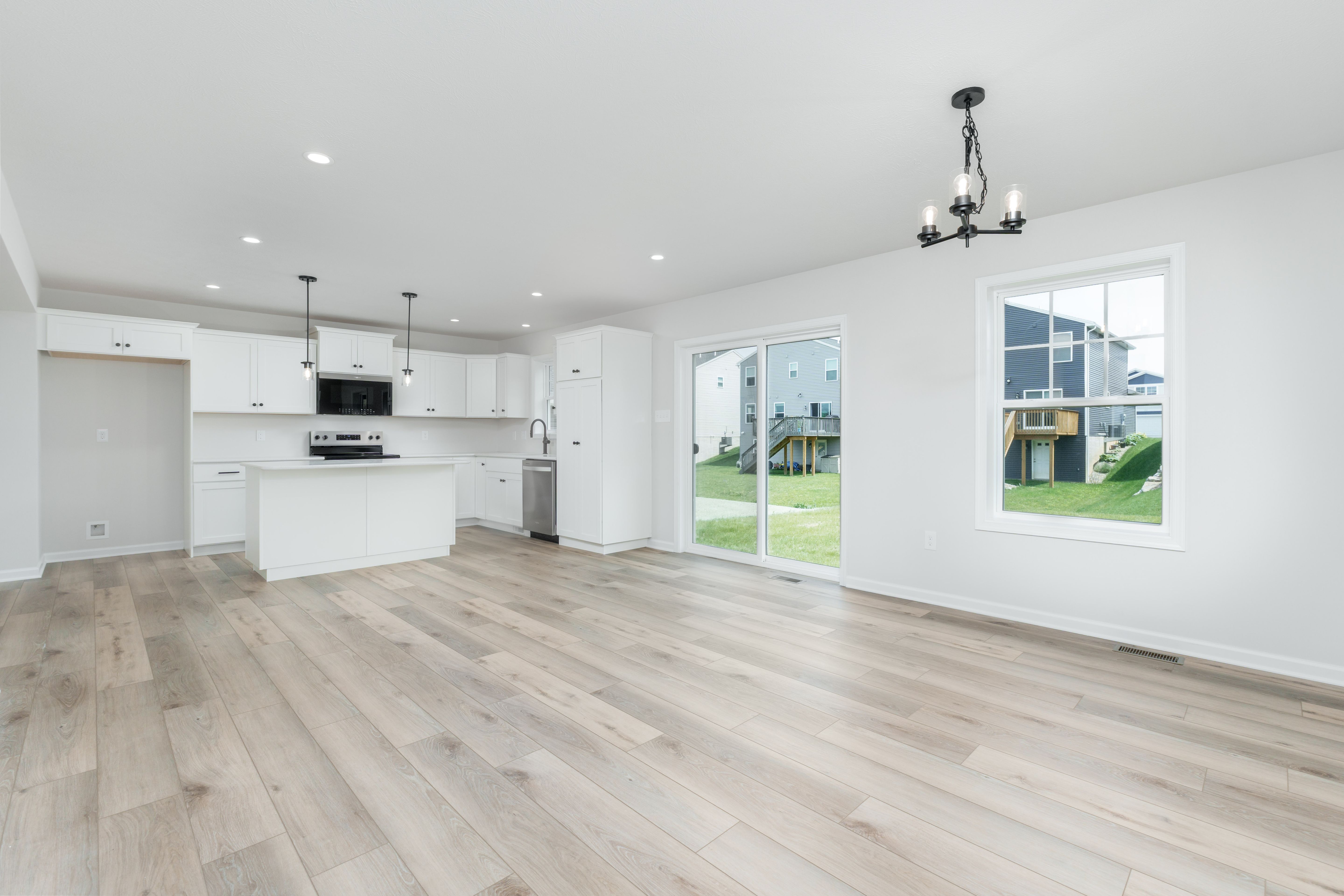 Open kitchen and breakfast space with white cabinetry, sliding door, and luxury vinyl plank floors.