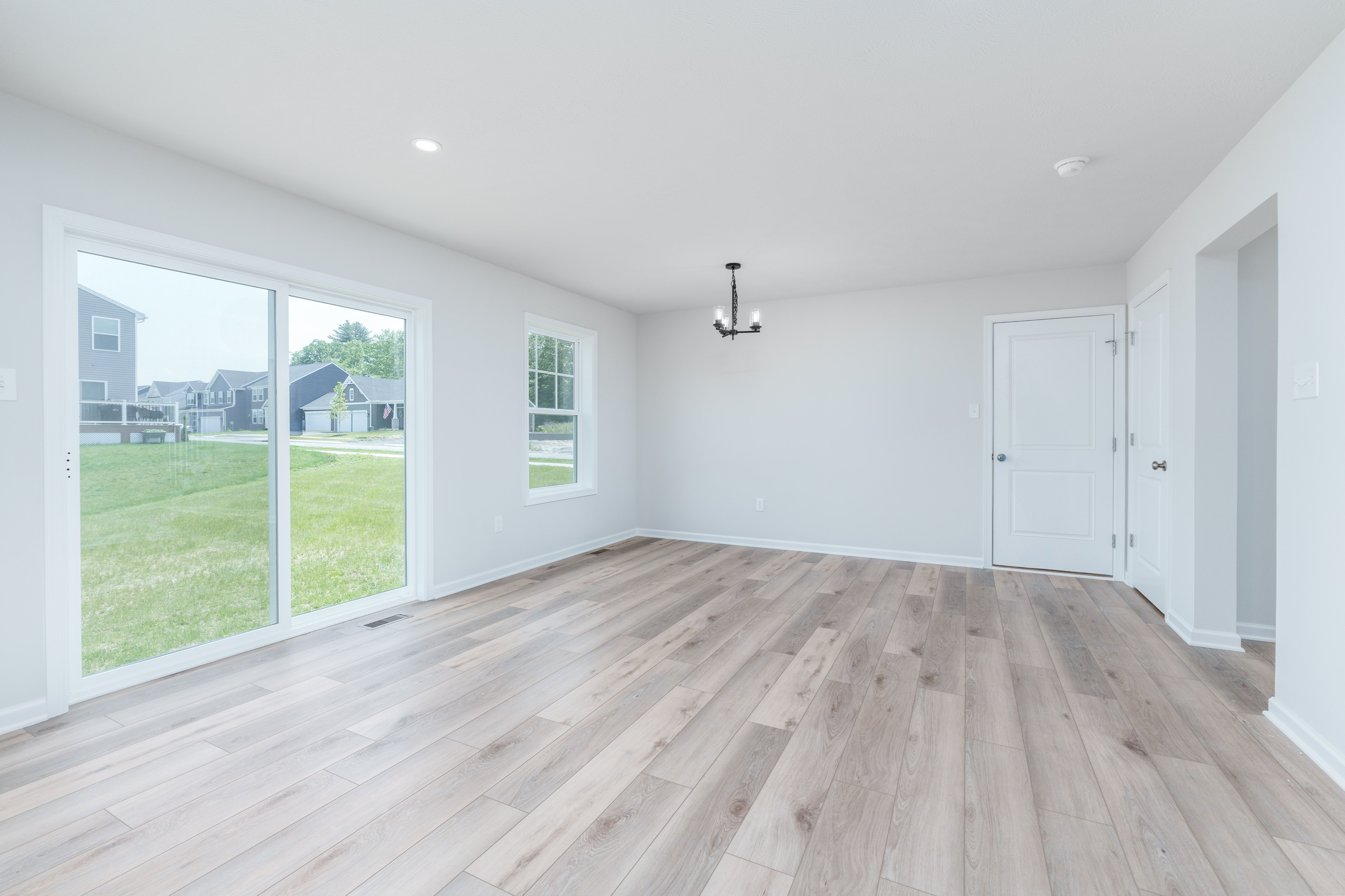 Kitchen view from island with pendant lights above and breakfast area in background.