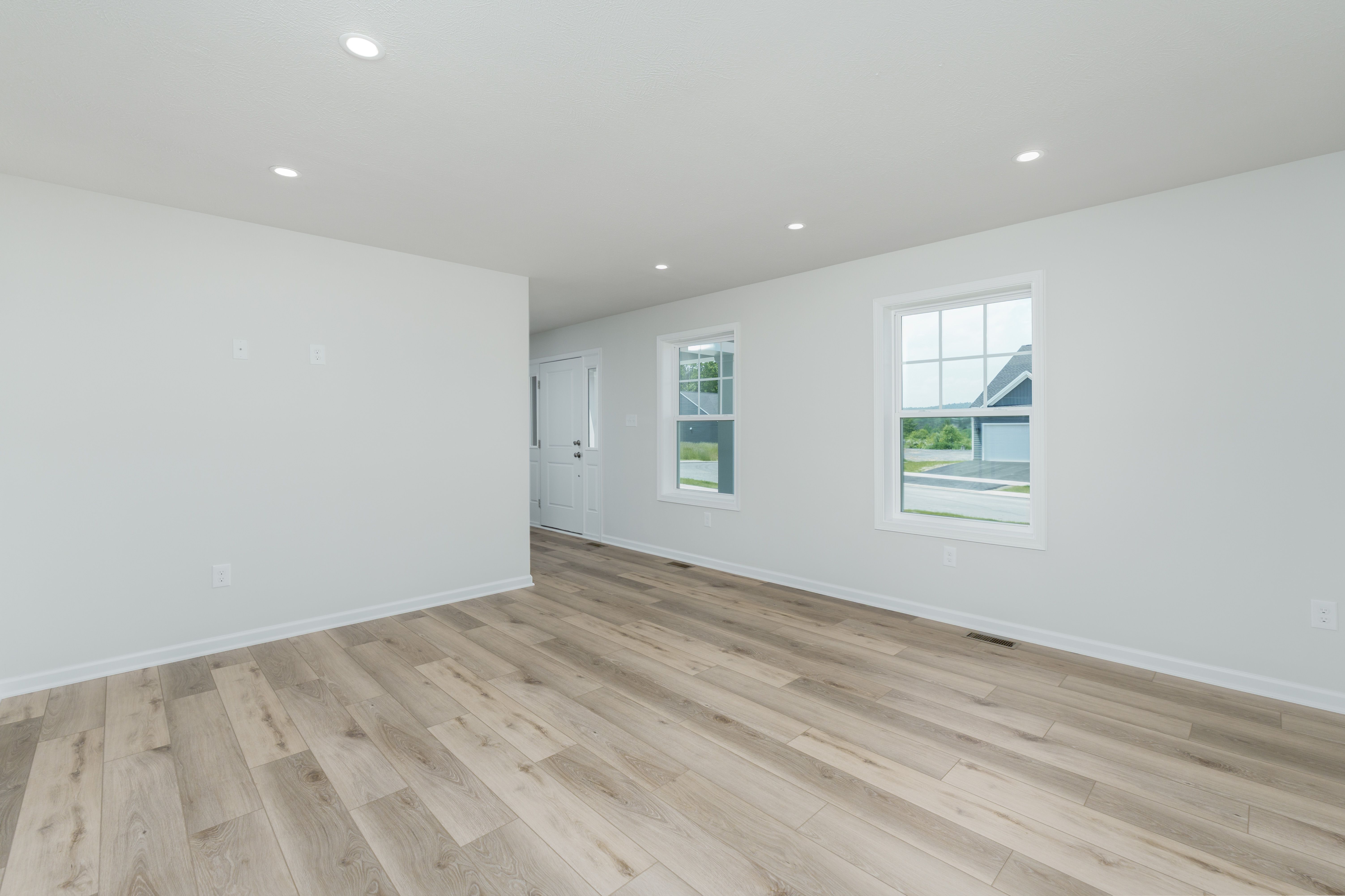 Family room with large window, luxury vinyl plank floors, and entry door with sidelights.