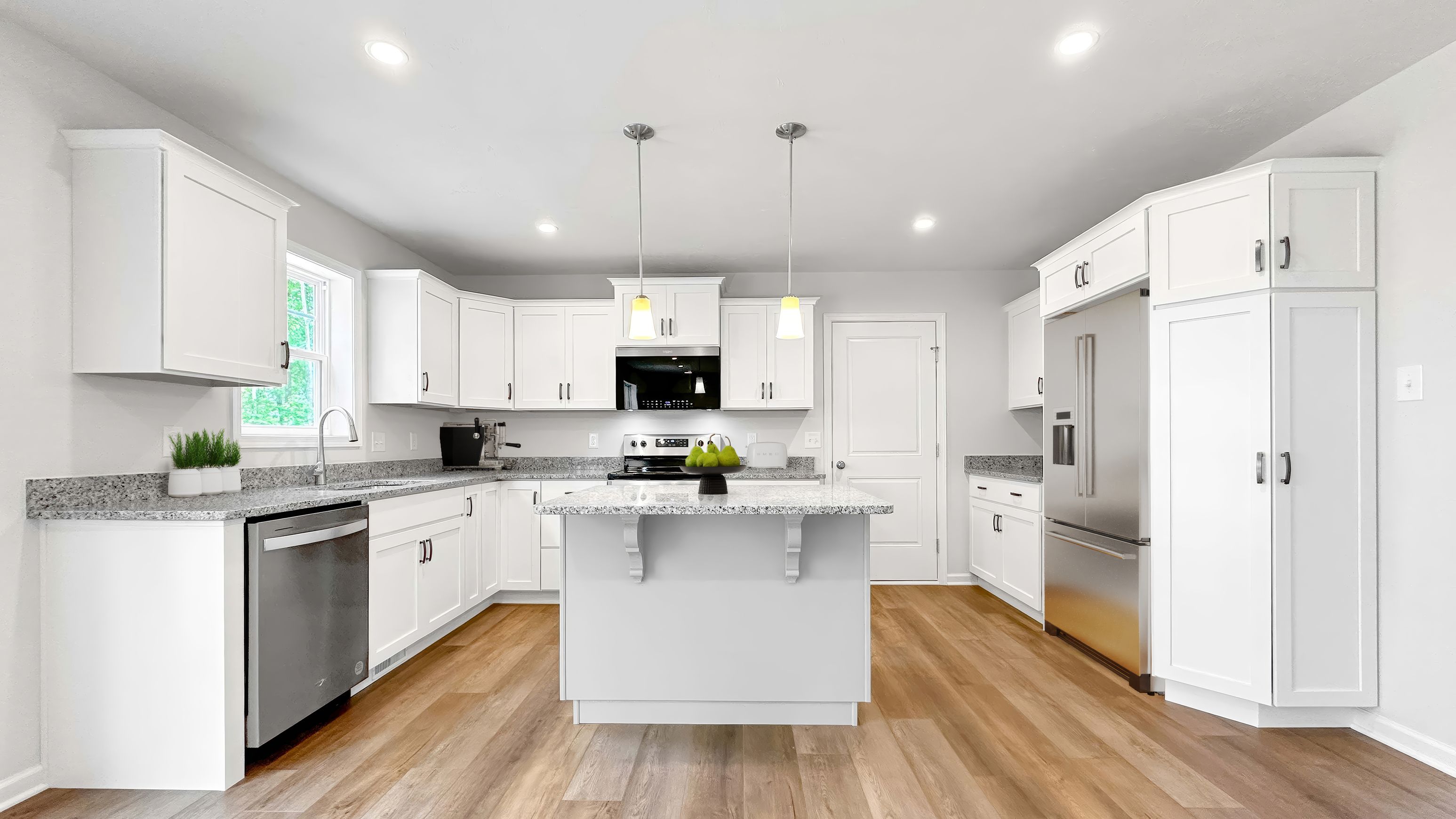 Bright kitchen with white cabinetry, granite countertops, stainless appliances, center island, and pendant lighting.
