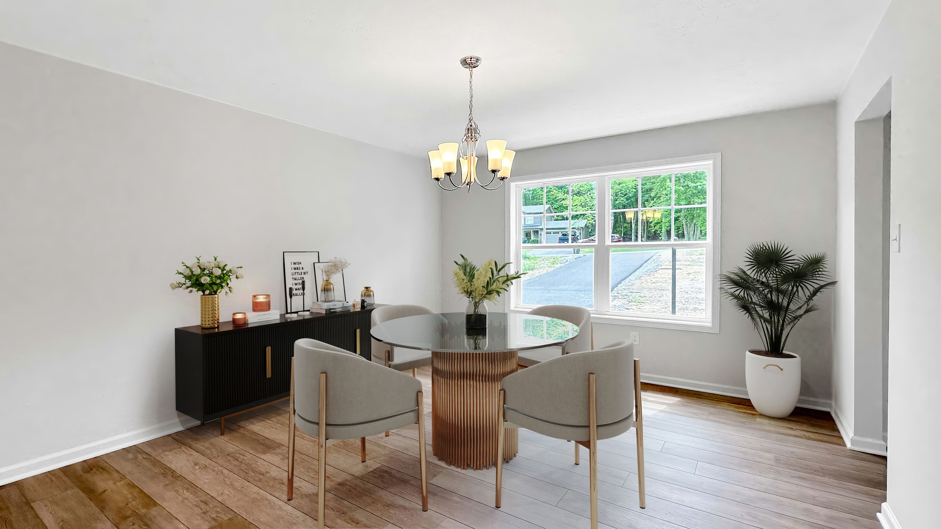 Dining room featuring a round glass table, upholstered chairs, modern chandelier, and large window overlooking the front yard.