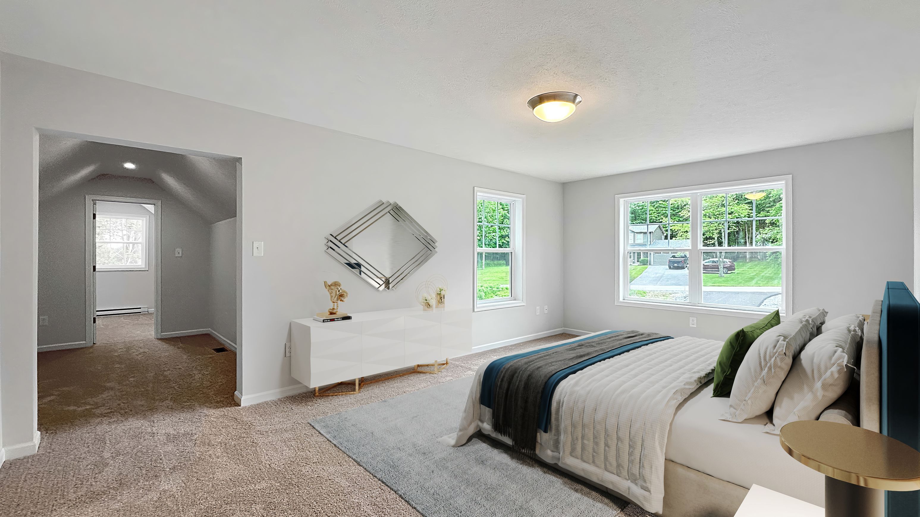 Primary bedroom suite showcasing a sitting area, stylish furnishings, large windows, and access to an additional space.