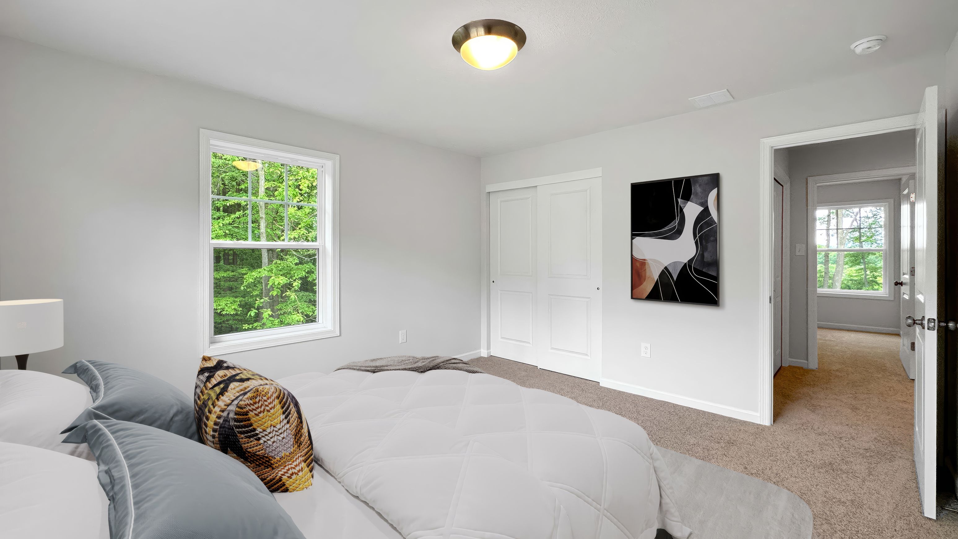 Bedroom featuring plush bedding, neutral walls, closet doors, and views into the hallway and outdoors.