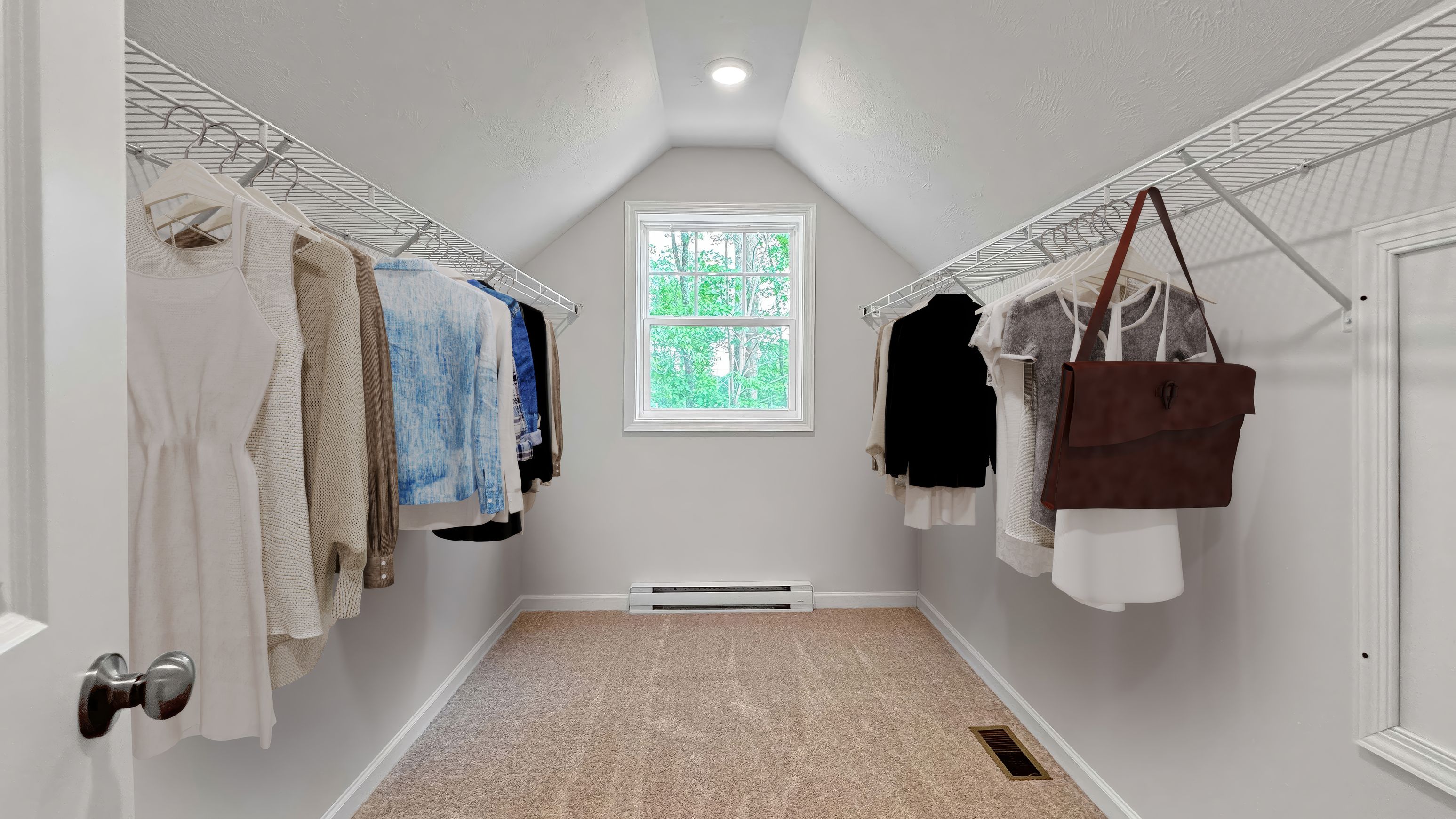 Walk-in closet with wire shelving, neatly hanging clothes, carpet flooring, and a window offering natural light.