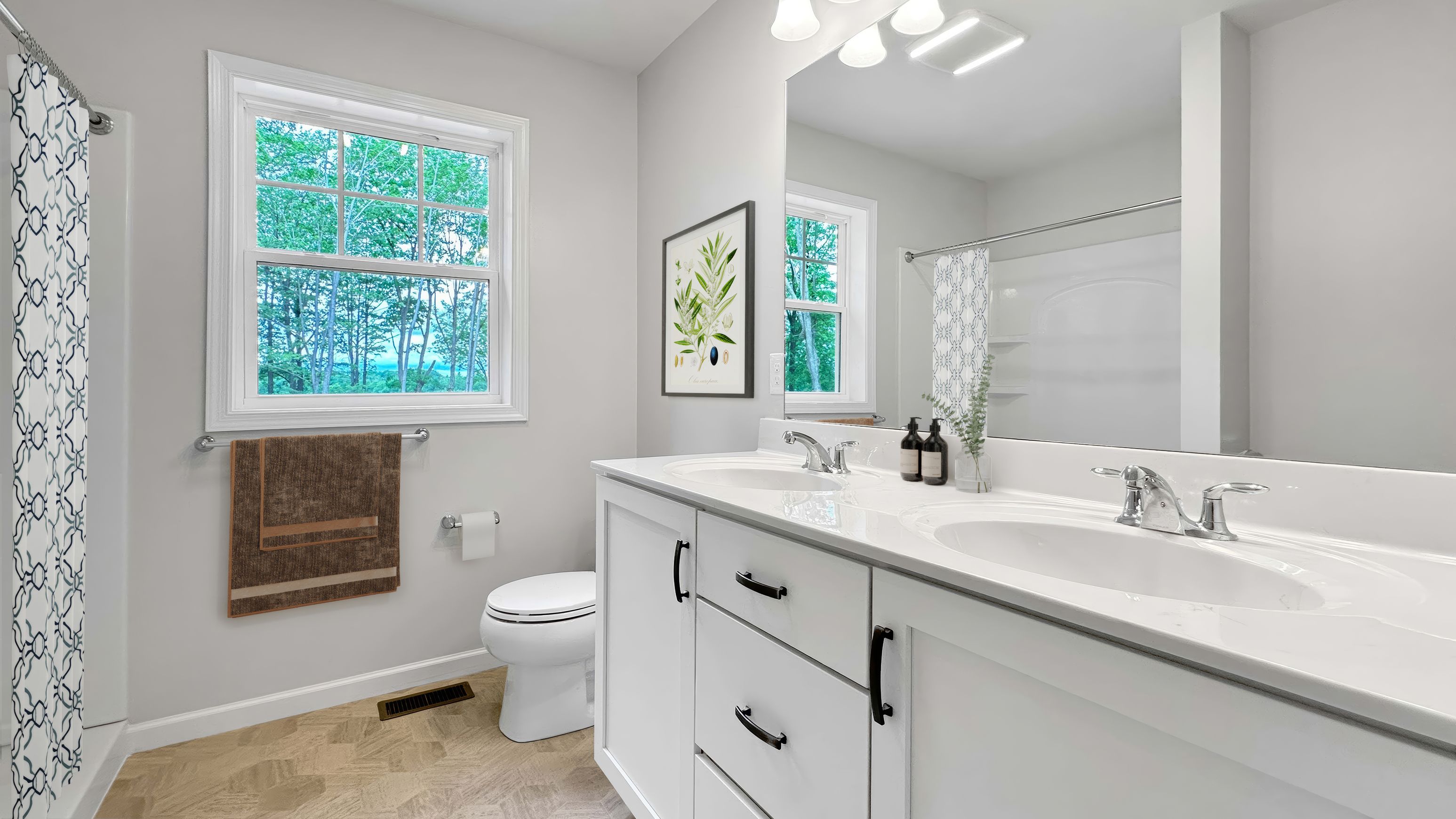 Modern bathroom with double vanity, white cabinetry, shower, decorative accessories, and a window with nature views.