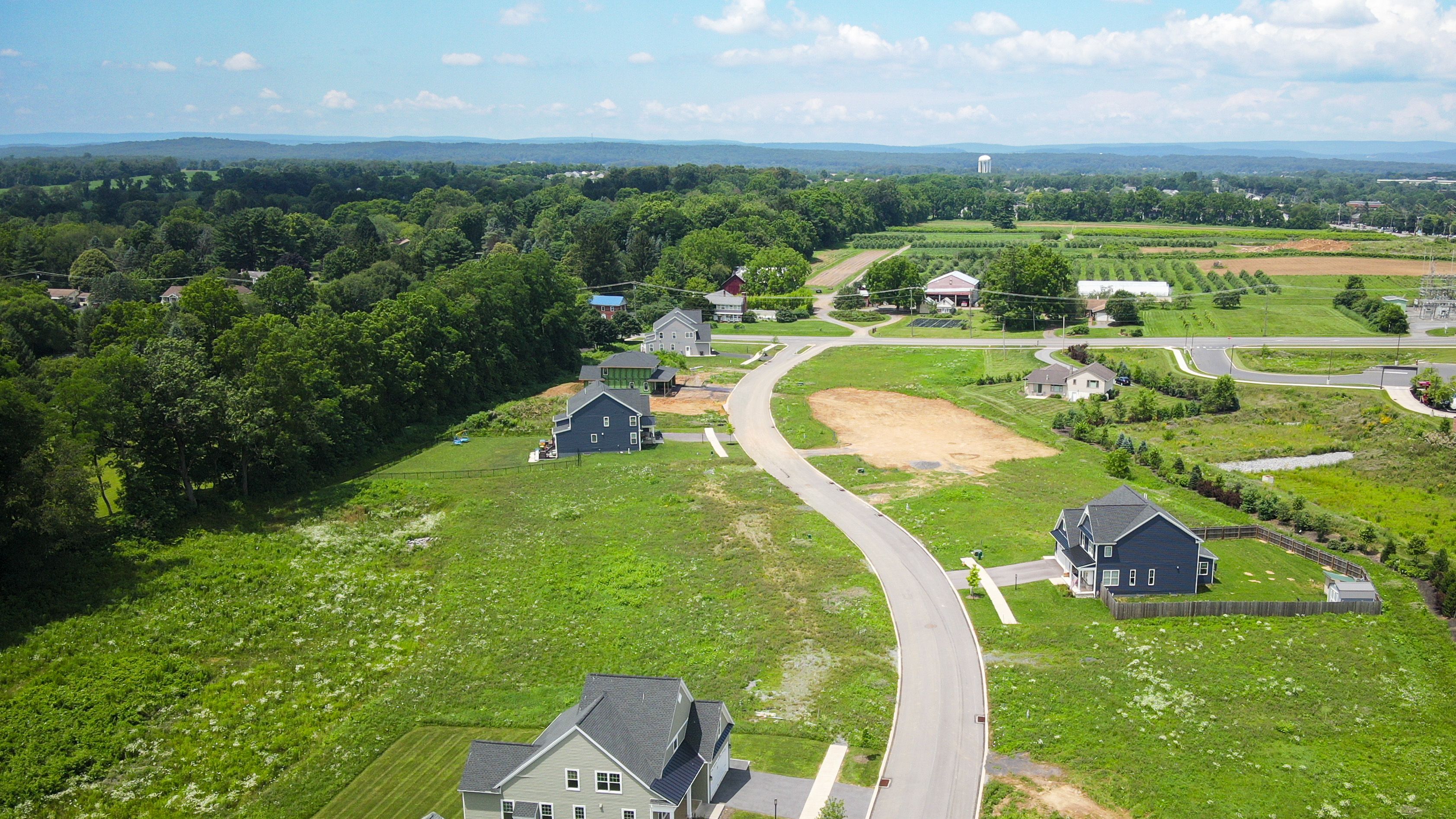Aerial view of neighborhood road curving through open lots and newly built homes