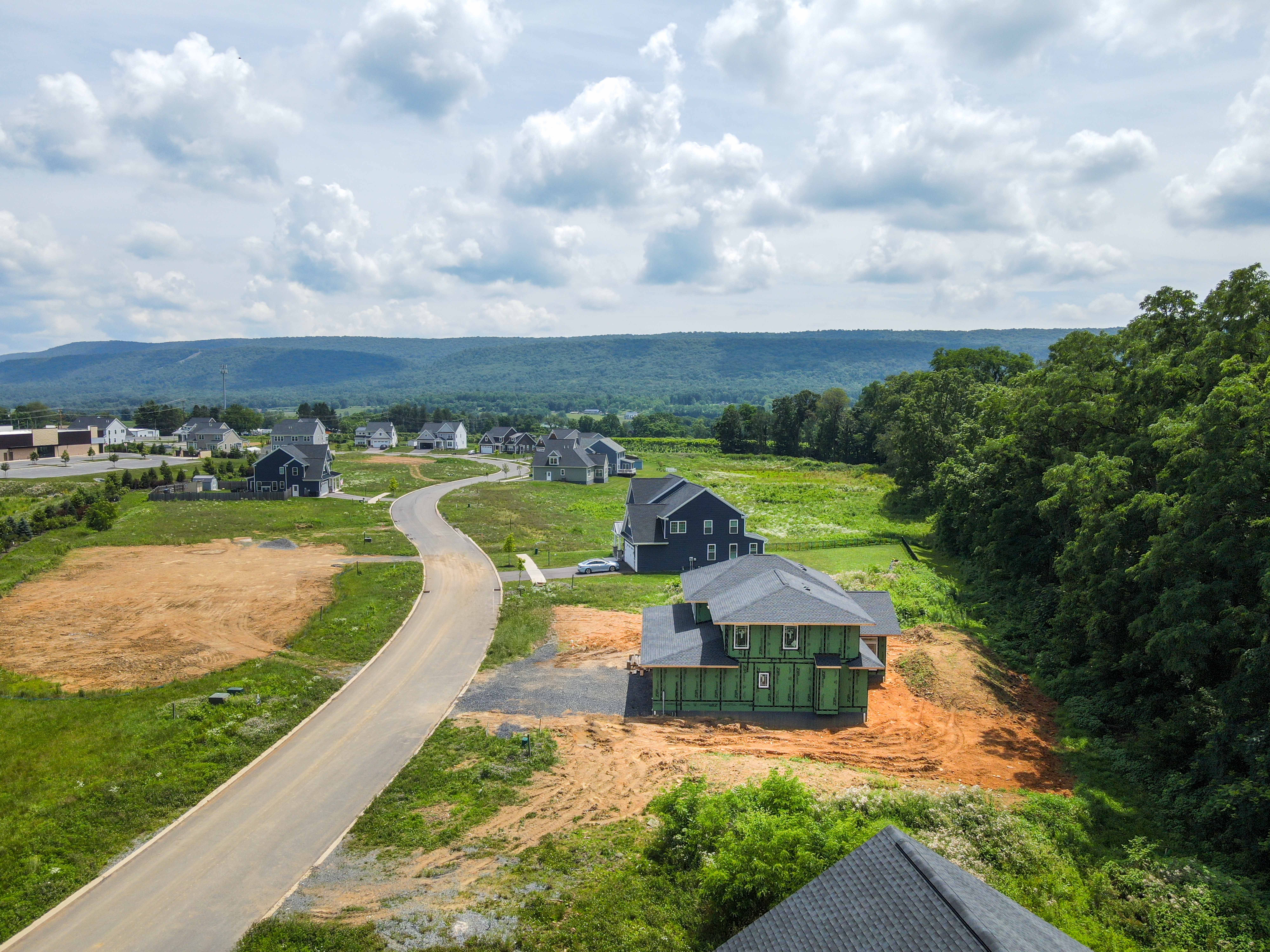 Winding road in new home community bordered by forest and scenic hills