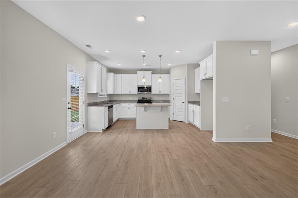 Open-concept kitchen and living area featuring wood-finish flooring, recessed lighting, white cabin