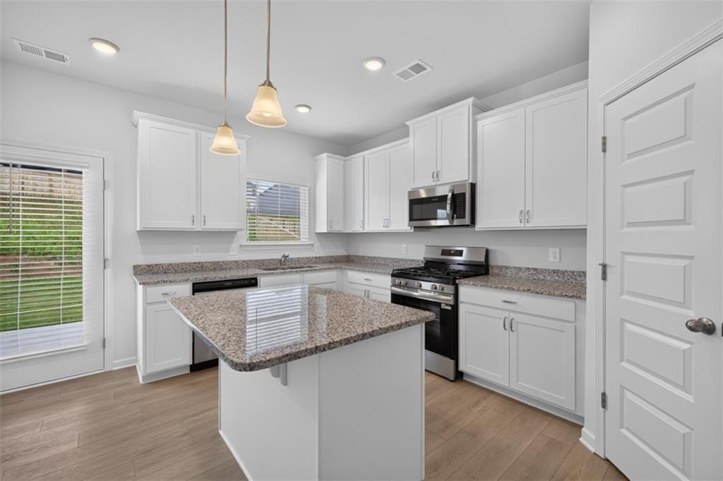 Modern kitchen featuring white cabinetry, granite countertops, and stainless steel appliances