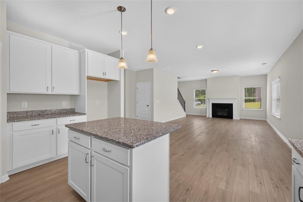 Open-concept living area featuring wood-finish flooring, a kitchen island with stone countertop, wh