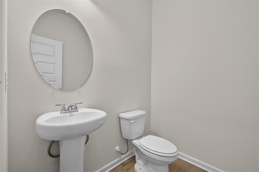 Pedestal sink with chrome faucet hardware and an oval frameless mirror