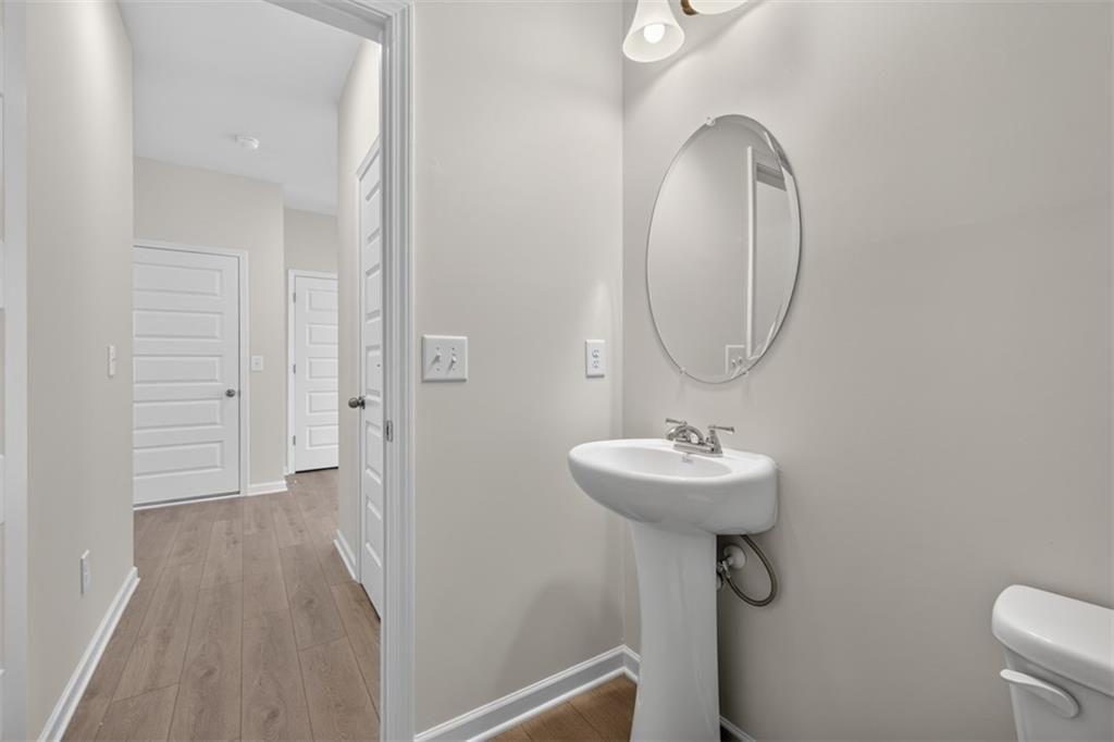Powder room featuring a pedestal sink with a chrome faucet, an oval mirror, and a two-light vanity
