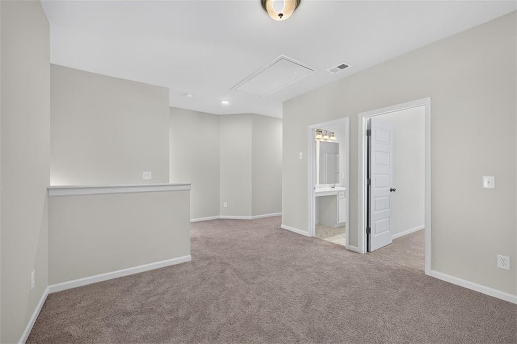 Carpeted loft area featuring neutral wall tones, white trim, and a semi-flush mount ceiling fixture