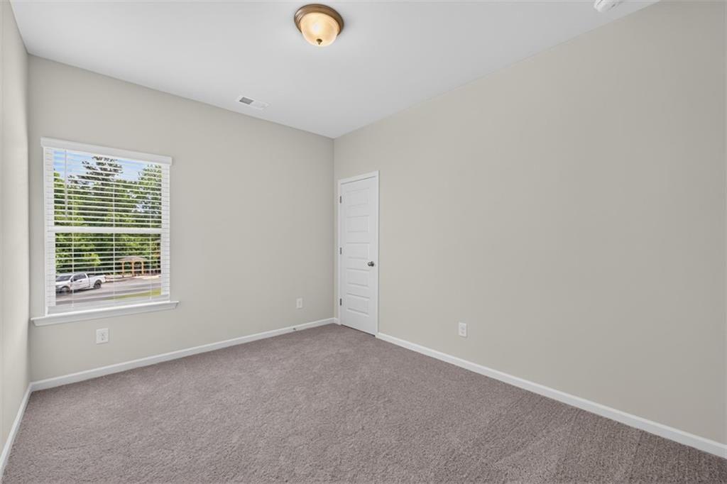 Carpeted room featuring a single window with horizontal blinds, a white paneled door, and neutral w