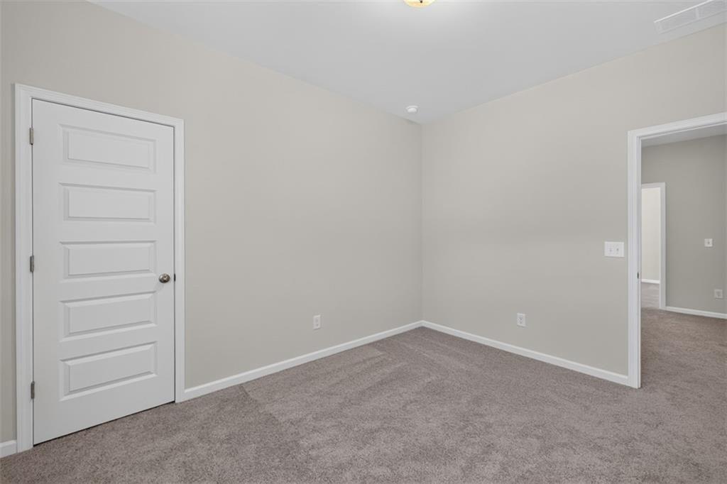 Room featuring light gray wall paint, gray carpet flooring, white trim, and a five-panel interior d