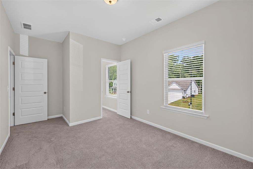 Carpeted room featuring multiple windows with blinds, white trim, and light gray walls