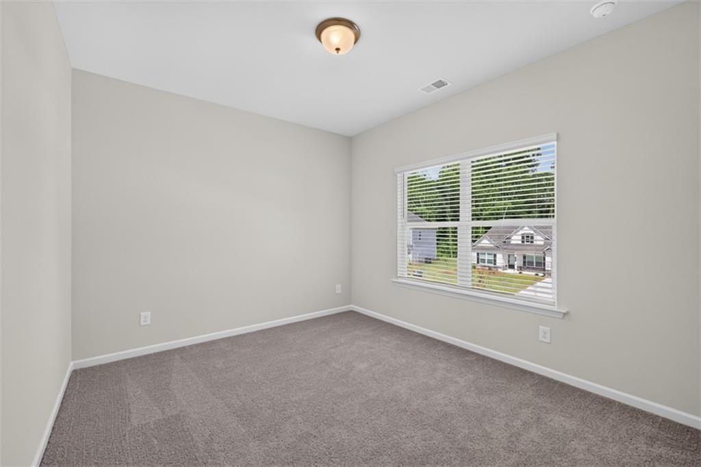 Neutral-toned room featuring a large window with horizontal blinds, gray carpeting, white baseboard