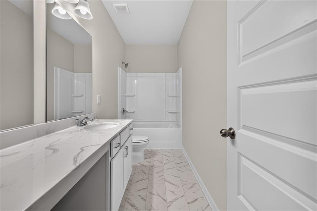 Bathroom featuring a single vanity with a white countertop and integrated sink, under-sink cabinetr