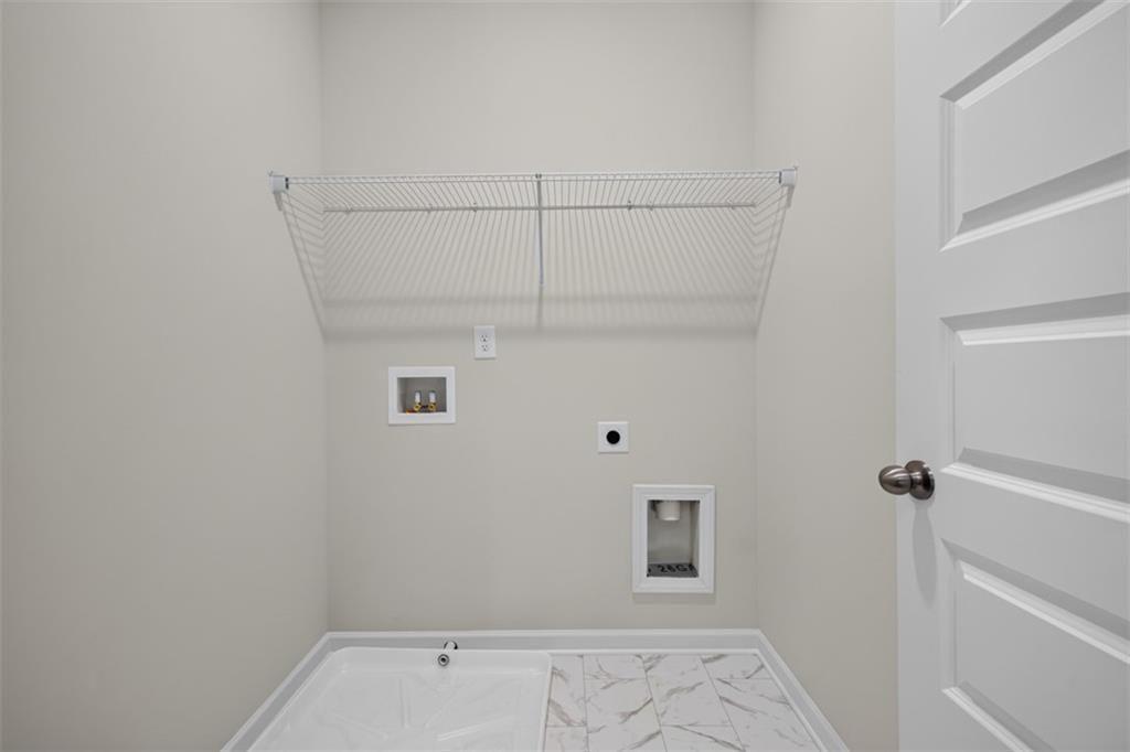Utility space featuring a wire shelving unit, appliance hookups, and a white tile floor