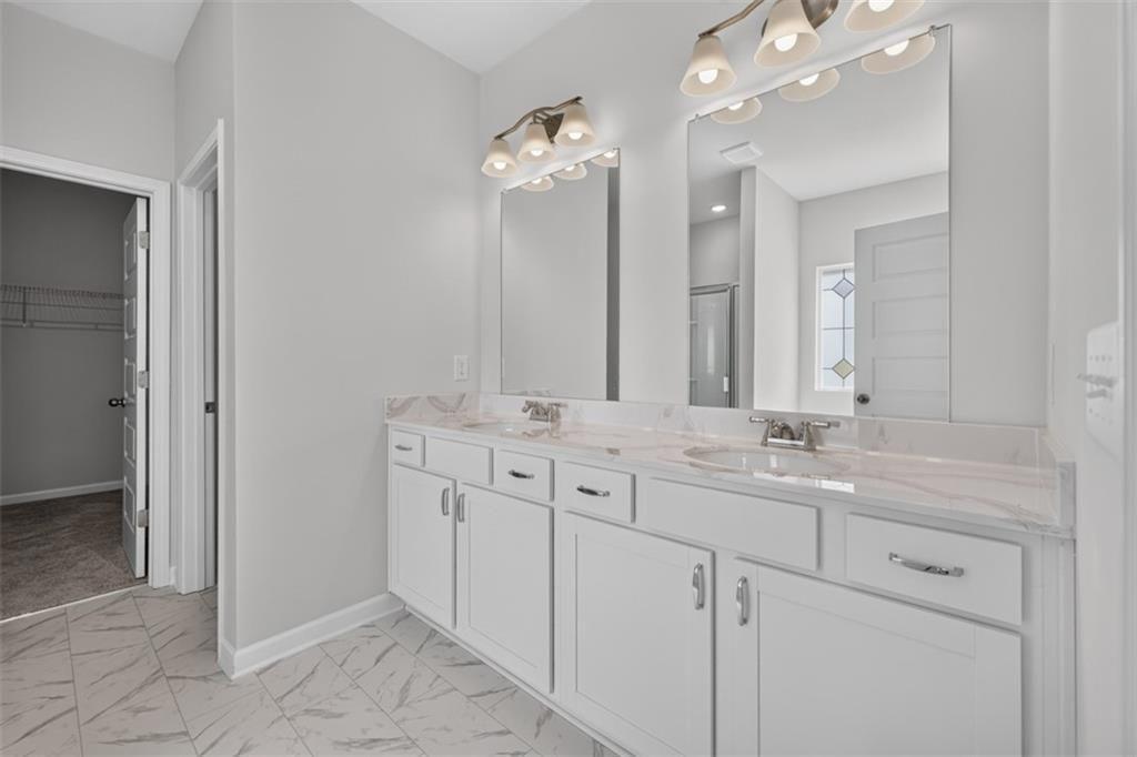 Double vanity featuring white cabinetry, undermount sinks, and stone-finish countertops