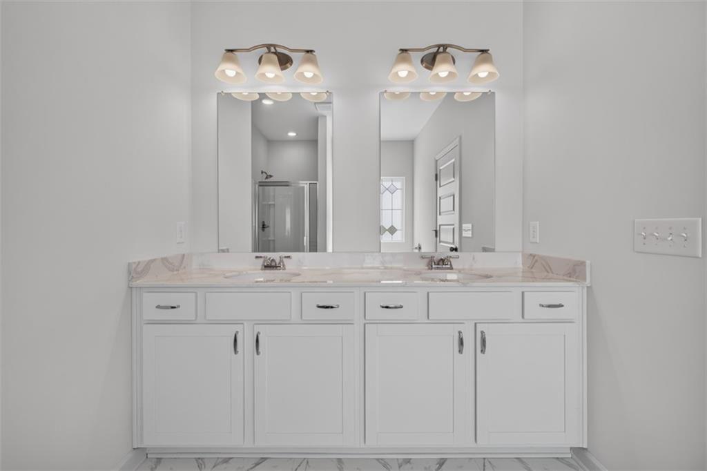 Double vanity featuring white cabinetry, light-toned countertops, and dual mirrors with integrated