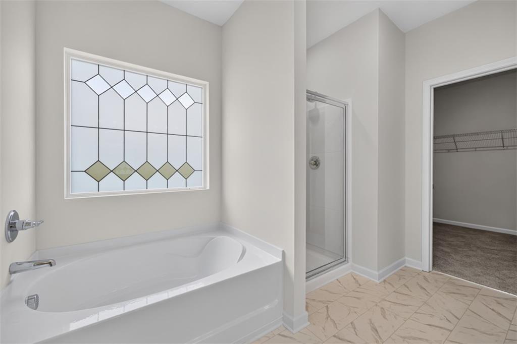 Soaking tub with chrome fixtures and an oversized opaque geometric window