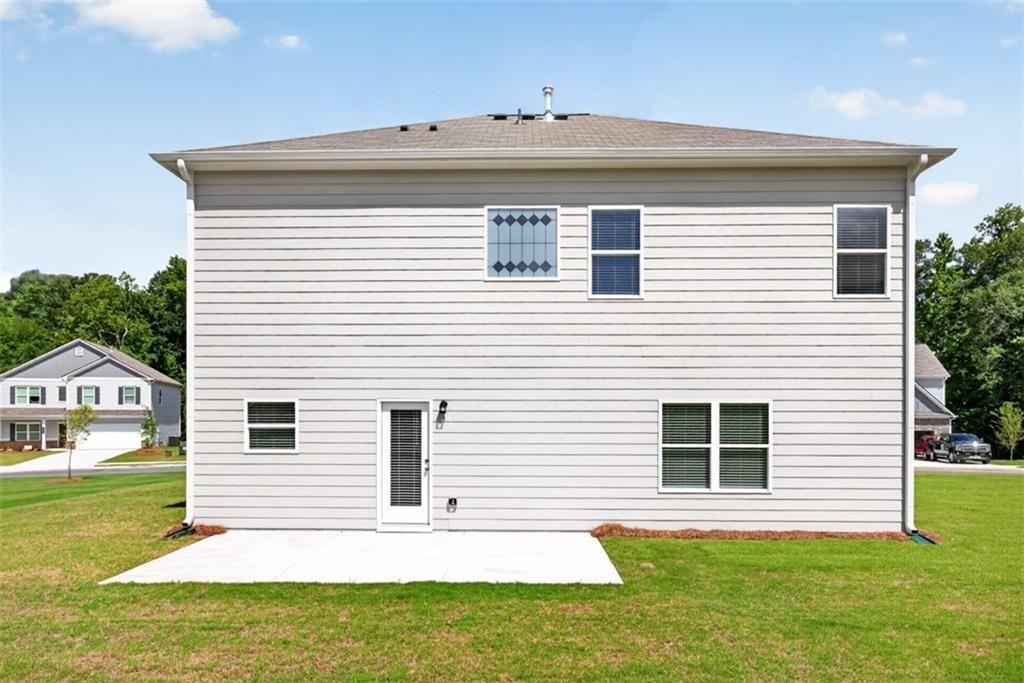 Rear exterior featuring light-colored siding, a concrete patio, and multiple windows