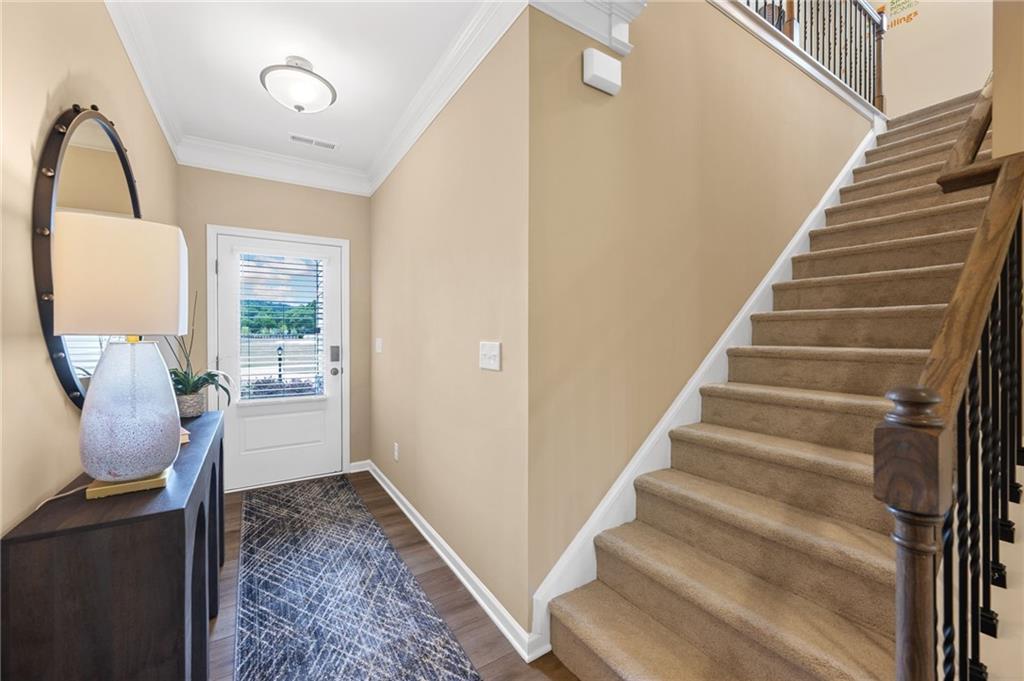 Entryway featuring wood-finish flooring, a white paneled door with integrated blinds, and a flush-mount ceiling light