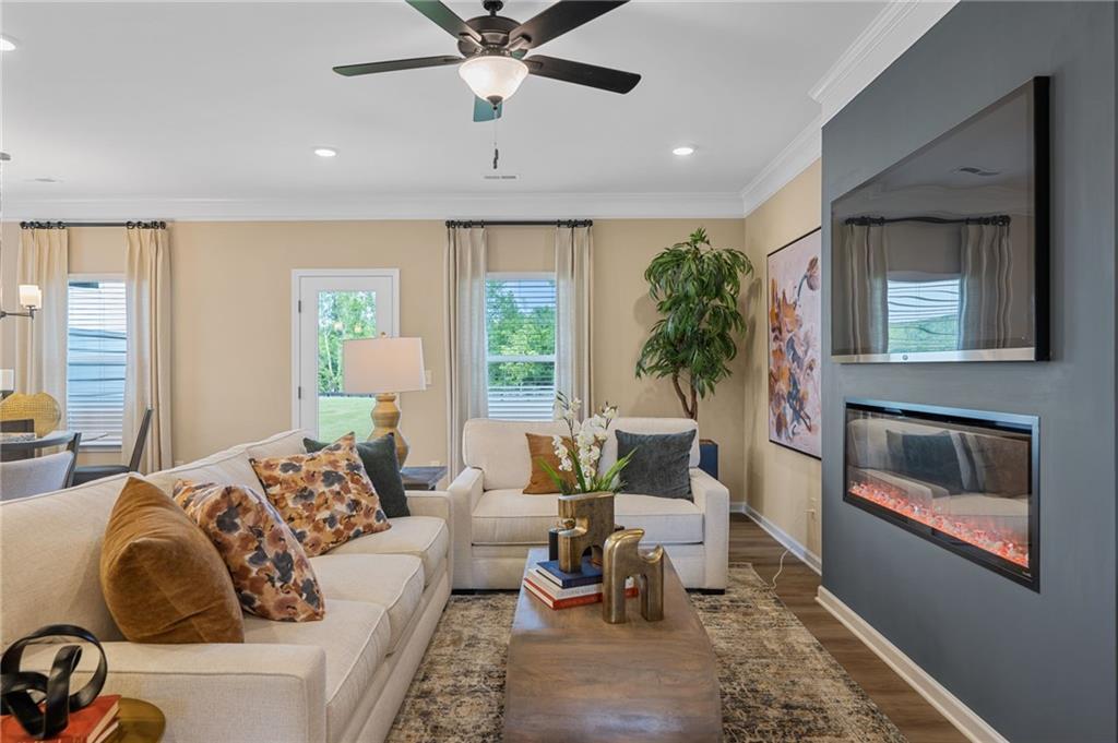 Recessed lighting illuminates the living area with a ceiling fan, crown molding, and wood-finish flooring