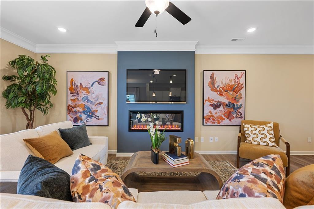 Recessed lighting, crown molding, ceiling fan, accent wall, and built-in electric fireplace