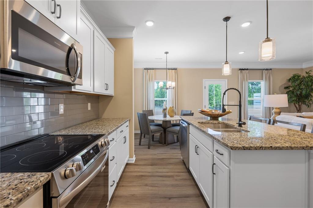 Kitchen featuring stainless steel appliances, white cabinetry, granite countertops, and wood-finish flooring