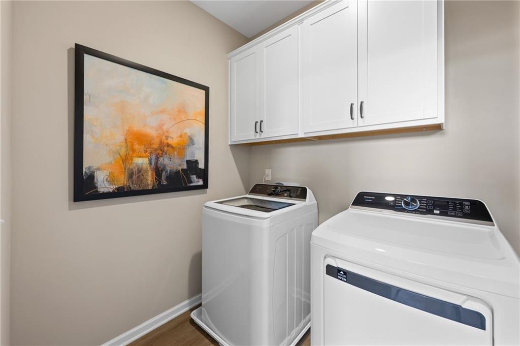 White shaker-style cabinetry with dark hardware, wood-finish flooring, and light wall paint