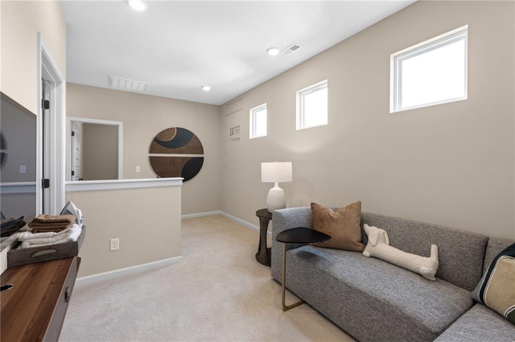 Carpeted loft area featuring neutral wall tones, recessed lighting, and multiple windows