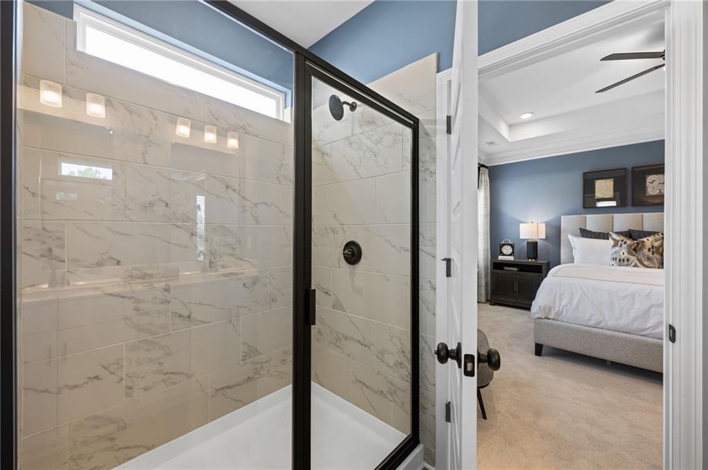 Shower with marble-finish tile walls, black-framed glass enclosure, and transom window