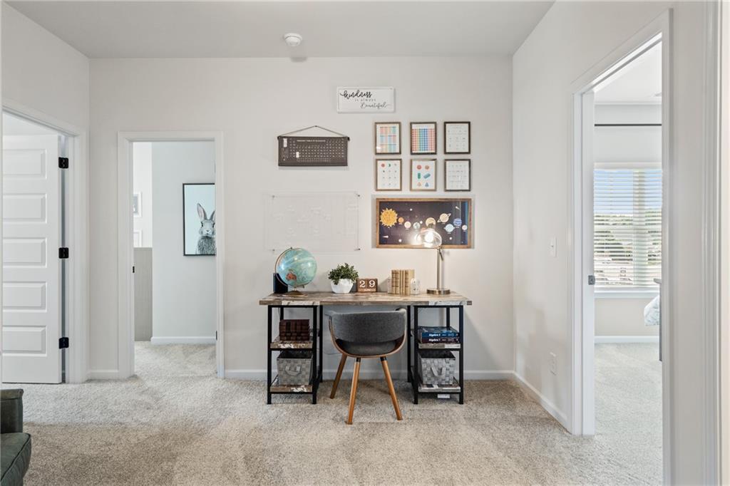 Carpeted hallway featuring multiple doorways and a recessed wall niche