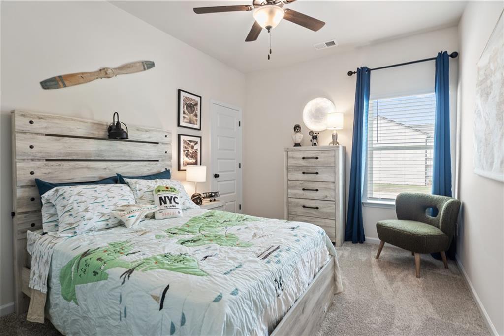 Recessed window with blinds, light-toned carpeting, ceiling fan with integrated lighting, and a solid interior door