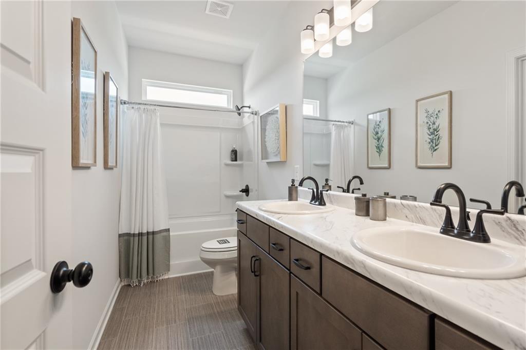 Dual vanity with undermount sinks, wood-finish cabinetry, and matte black fixtures