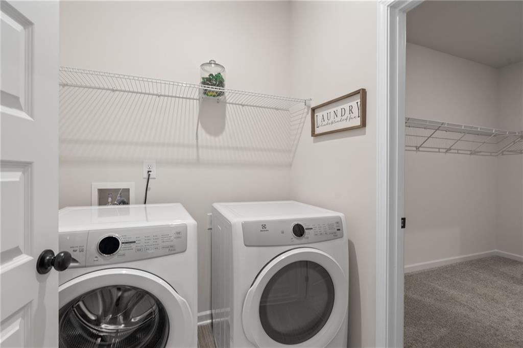 Laundry area featuring a side-by-side appliance configuration, wire shelving, and wood-finish flooring