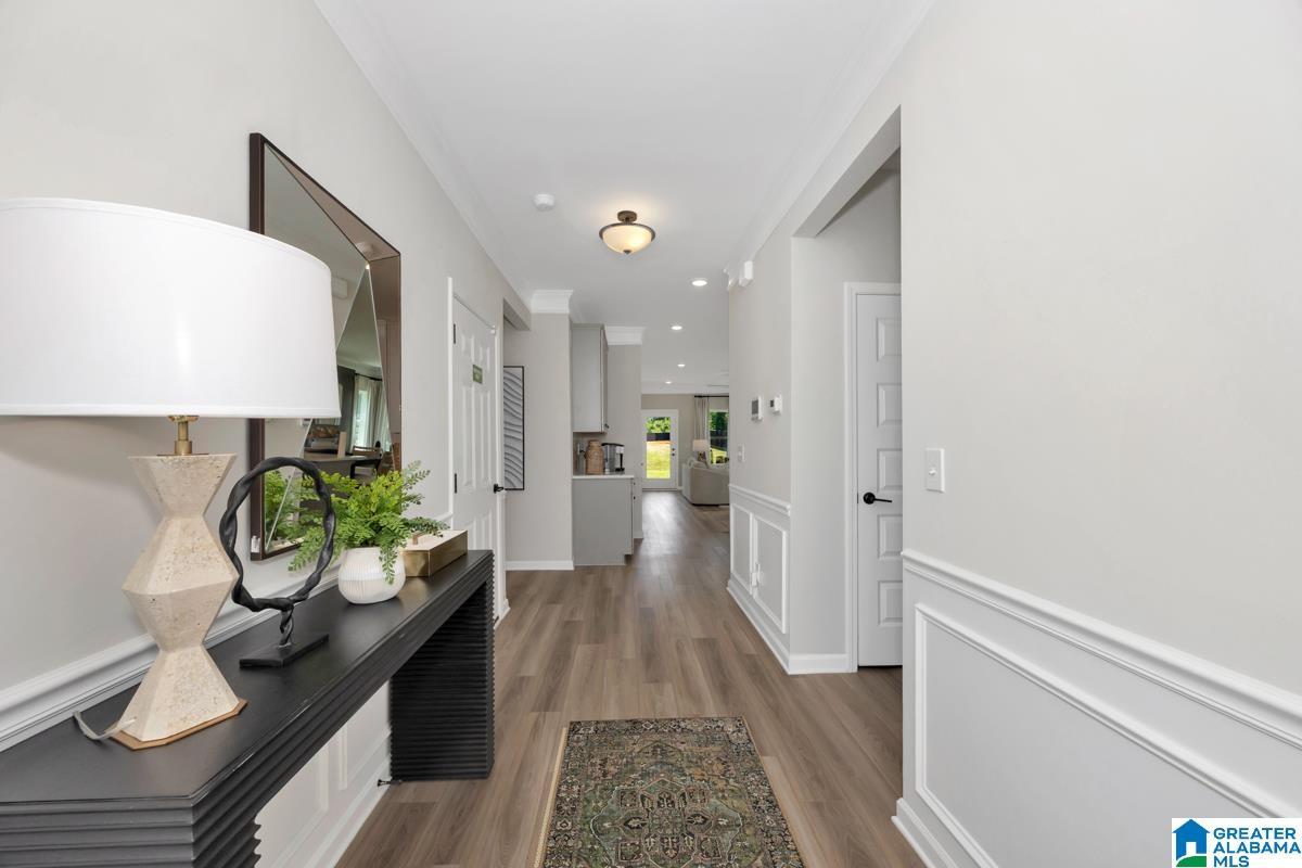 Wood-finish flooring, white paneled wainscoting, crown molding, and recessed lighting