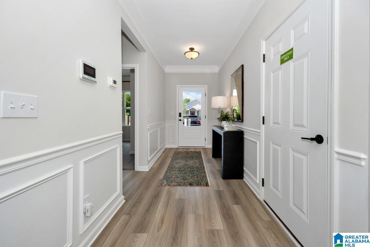 Wood-finish flooring, wainscoting, crown molding, paneled doors, and a glass-paneled entry door