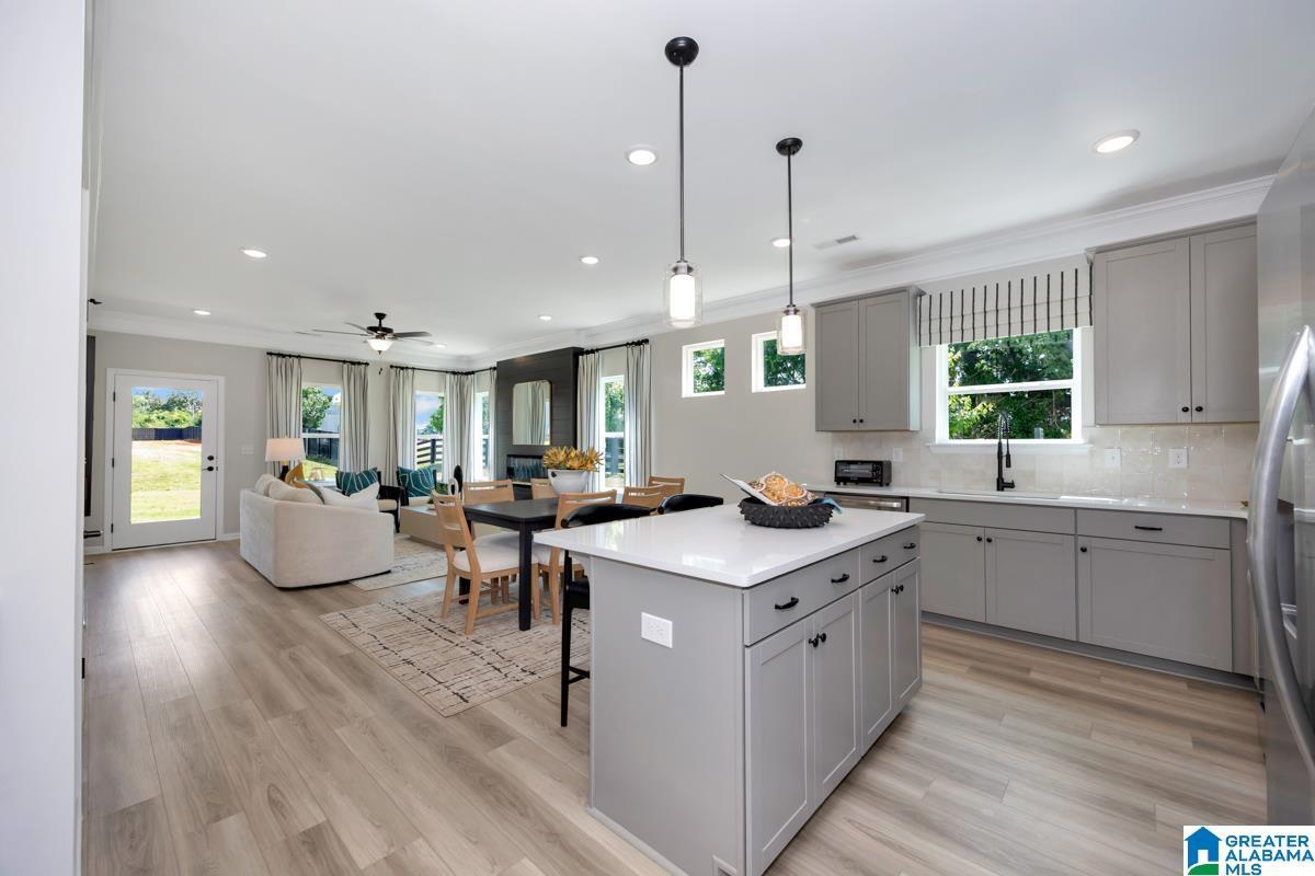 Open-concept living space featuring wood-finish flooring, recessed lighting, and a kitchen island with pendant lighting