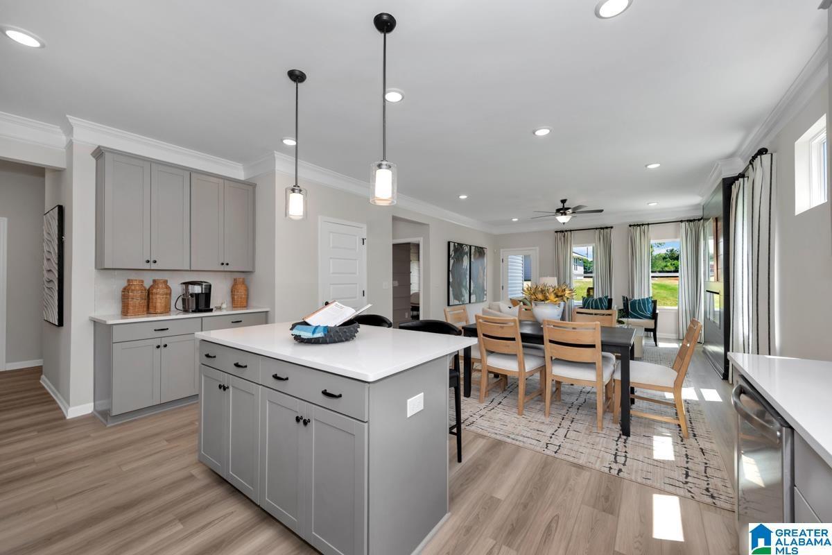 Kitchen featuring an island with built-in cabinetry, shaker-style cabinets, pendant lighting, wood-finish flooring, and recessed lighting